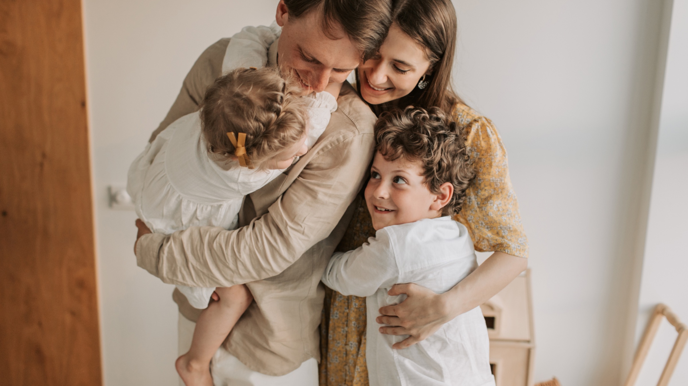 A family of four sharing a warm embrace at home